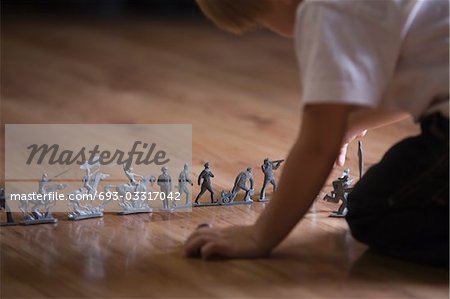 Boy playing with toy soldiers on floor