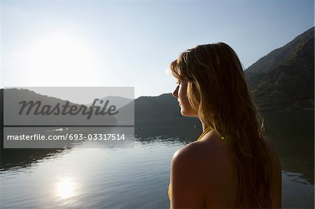Blonde woman looks out across morning sunrise over lake