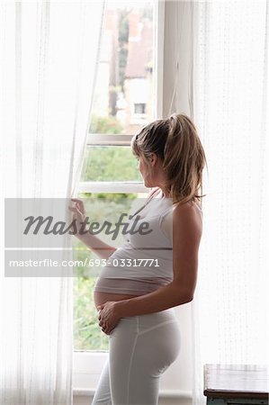 Pregnant woman looking out of window
