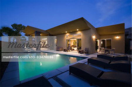 Lit swimming pool and house exterior at night