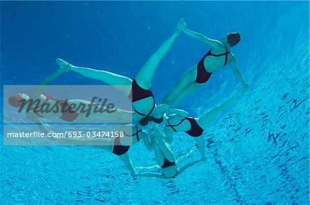 Synchronised swimmers form a star, underwater view