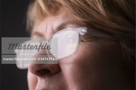 Mature woman with light reflecting on reading glasses