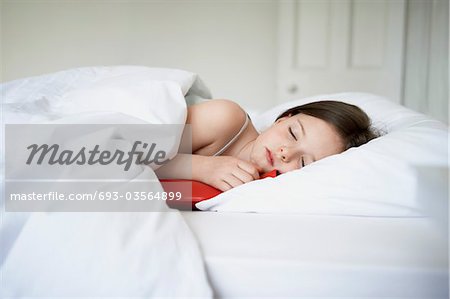 Little girl with cold in bed holding hot water bottle