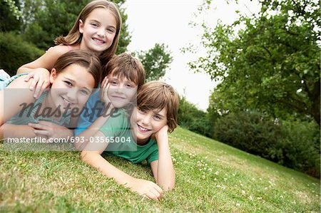 Two young girls and boys lying in park together, portrait