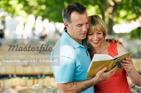 Mid-adult couple in park looking at book together
