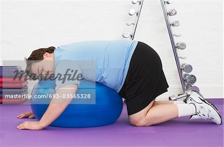 Overweight Man sleeping on Exercise Ball in health club