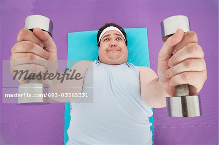 Overweight Man lying down Lifting dumbbells, overhead view