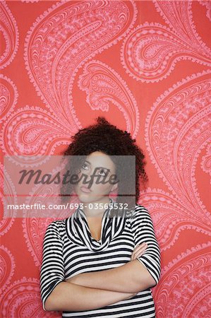 Teenage Girl in standing, arms crossed, looking away,  in front of  Colourful Wallpaper