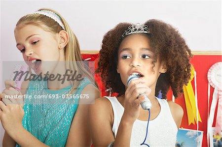 Girls using brushes, microphones to sing at a Slumber Party