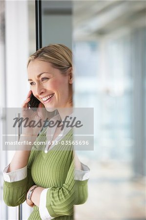 Business woman using mobile phone in office, portrait