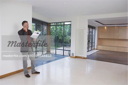 Real estate agent using mobile phone in new property