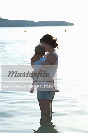 Mother holding son in knee-length water