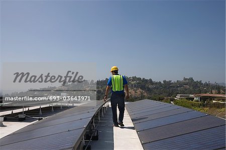 Maintenance worker checks solar array on rooftop in Los Angeles, California