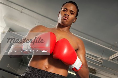 Boxer with red boxing gloves in gym, half length