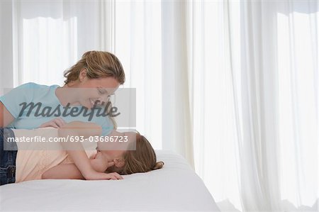 Mother and daughter lying on bed, half length