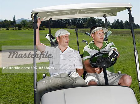 Two young male golfers sitting in cart