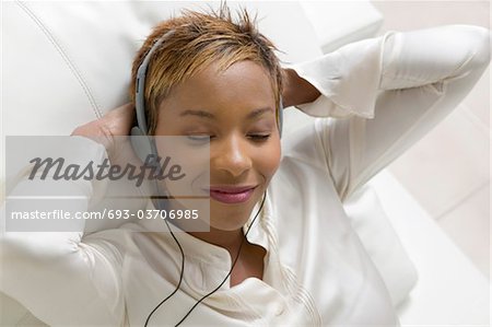 Woman lying on sofa Listening to Music on portable CD player, close up, overhead view