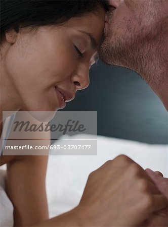 Close-up of mid-adult man kissing his girlfriend's forehead
