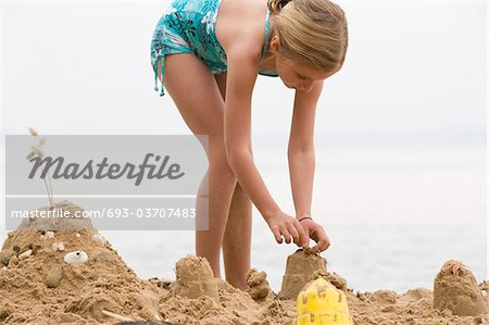 Pre-teen girl building sand castle on beach