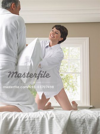 Couple having pillow fight on bed