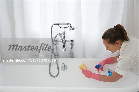 Young woman cleaning bathtub