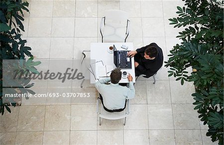 Businessmen using laptop at outdoor table, view from above