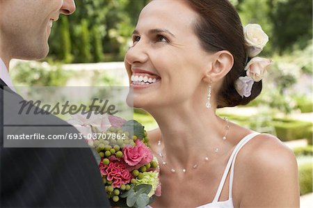 Mid adult bride and groom in garden, smiling, close-up