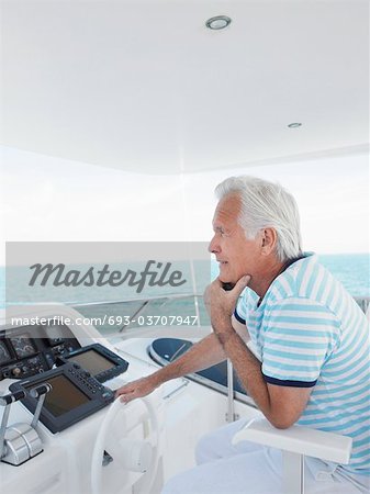 Middle-aged man sitting at helm of yacht, side view