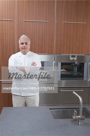 Mid- adult chef stands with arms folded