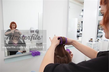 Stylist puts rollers in clients hair