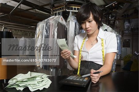 Woman working in the laundrette calculating receipts