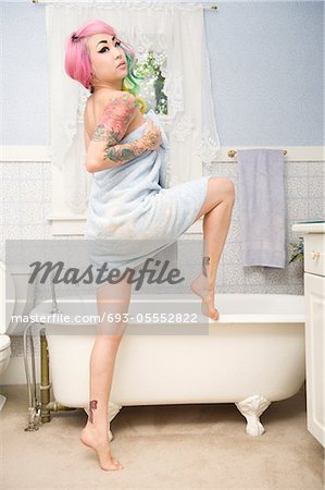 Young woman in towel posing in front of bathtub