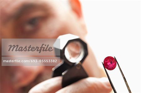 Close up of gemstone with jeweler looking through magnifying glass