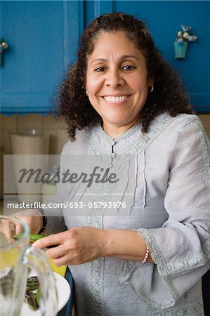 Smiling middle-aged woman cooking in kitchen