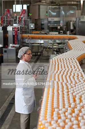 Man inspecting orange juice bottles at bottling plant