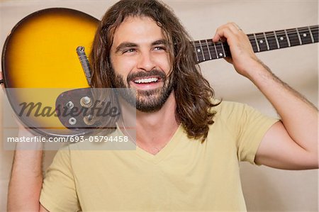 Happy man holding guitar on back of his shoulders