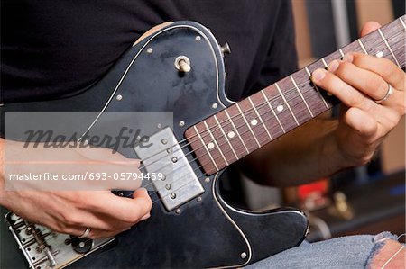 Close-up view of man playing electric guitar