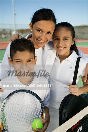 Mother with son and daughter by net on tennis court, portrait