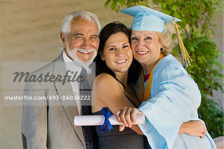 Senior graduate hugging granddaughter with husband outside