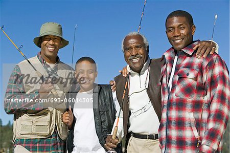 Male members of three generation family holding fishing rods outdoors, smiling, (portrait)