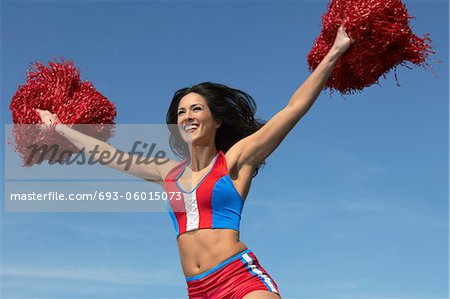 Cheerleader running with pom poms raised