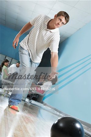 Young man releasing bowling ball, portrait