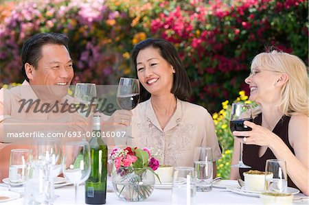 Three friends toasting at outdoor table