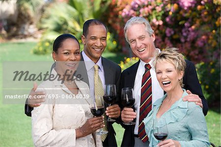 Two couples holding wine outdoors, portrait