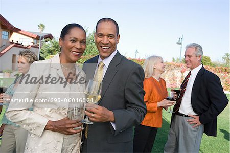 Couple holding drinks at outdoor party, portrait