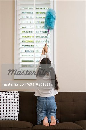 Girl (10-12) dusting window