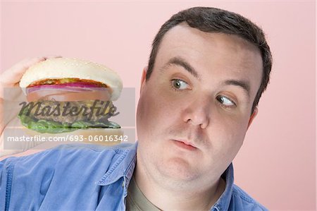Overweight mid-adult man holding hamburger