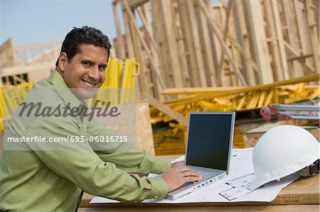 Construction worker using laptop, portrait