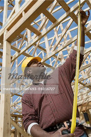 Construction worker measuring building