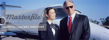 Businessman and Flight Crew Standing by Airplane